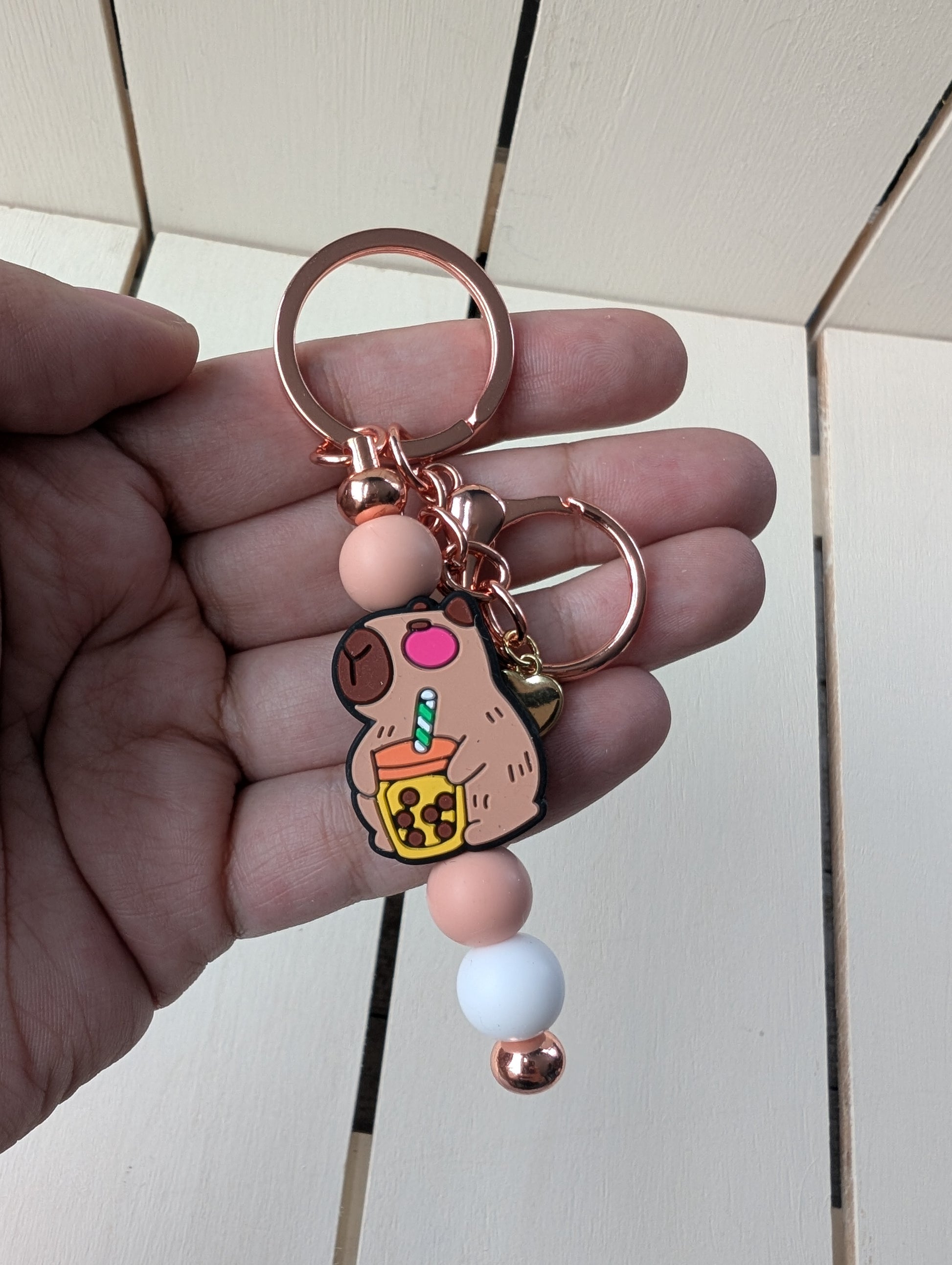 Capybara drinking from a boba tea beverage keychain.