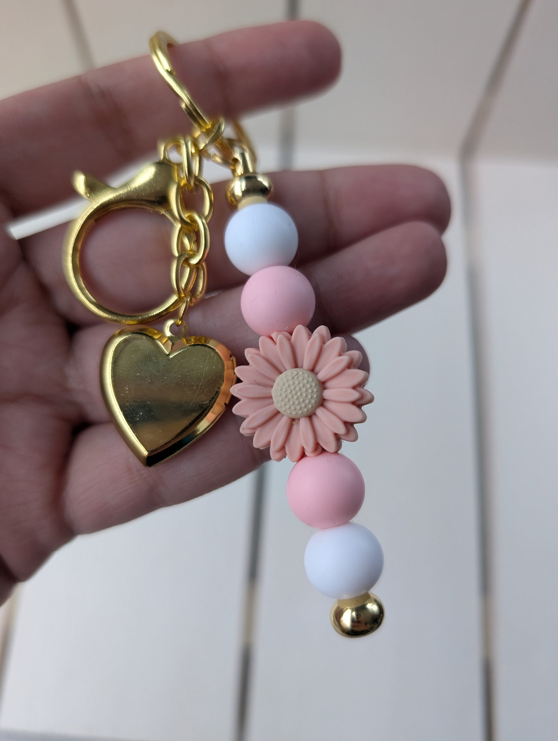 Flower keychain with gold heart locket charm.